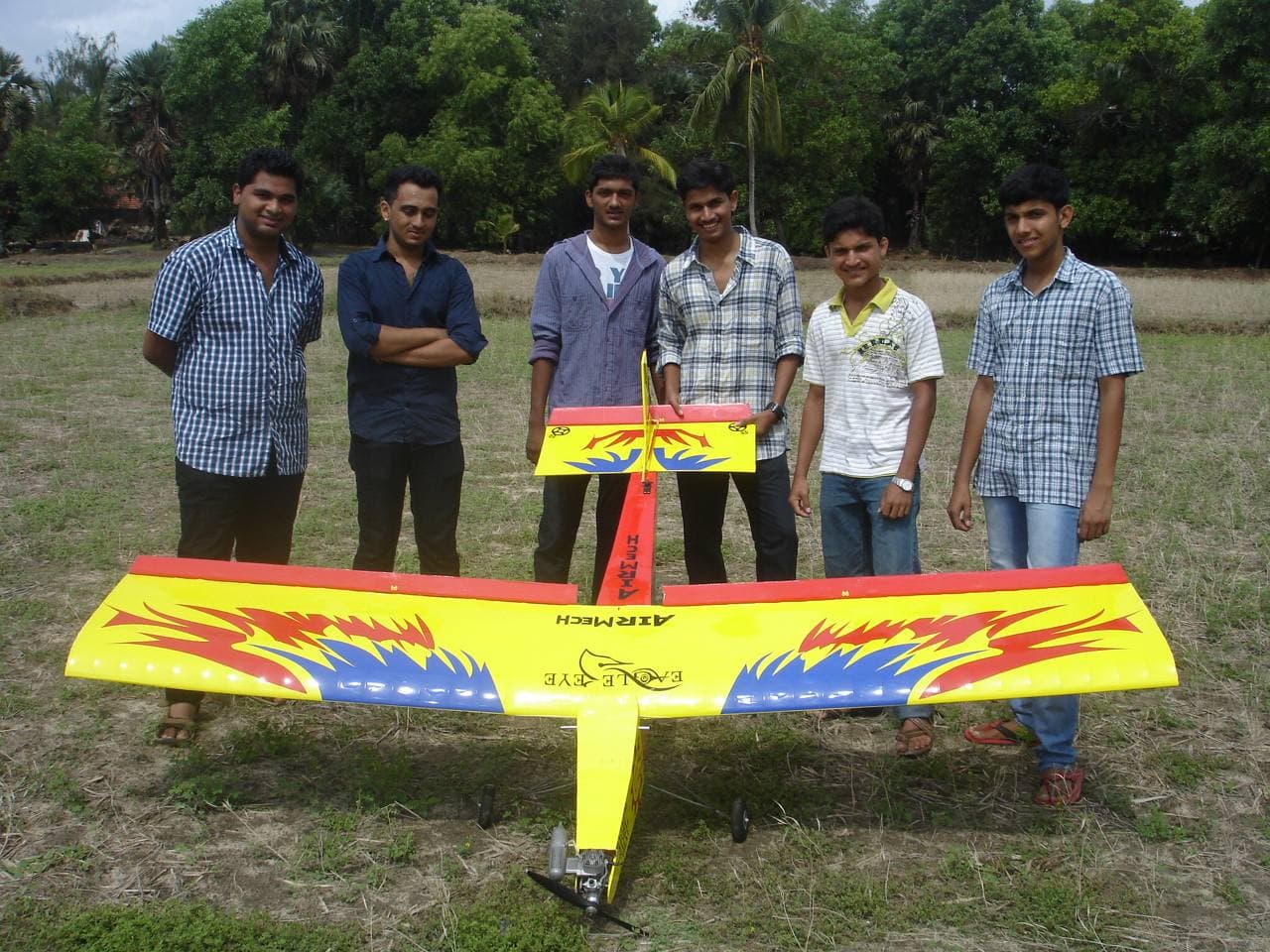 "A 10cc high-wing trainer aircraft designed as a college project, displayed with the student team in an open field."