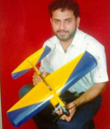 Pushhpraj Shrinivas Ameenn holding a control line aerobatic plane named Rascal against a red background.